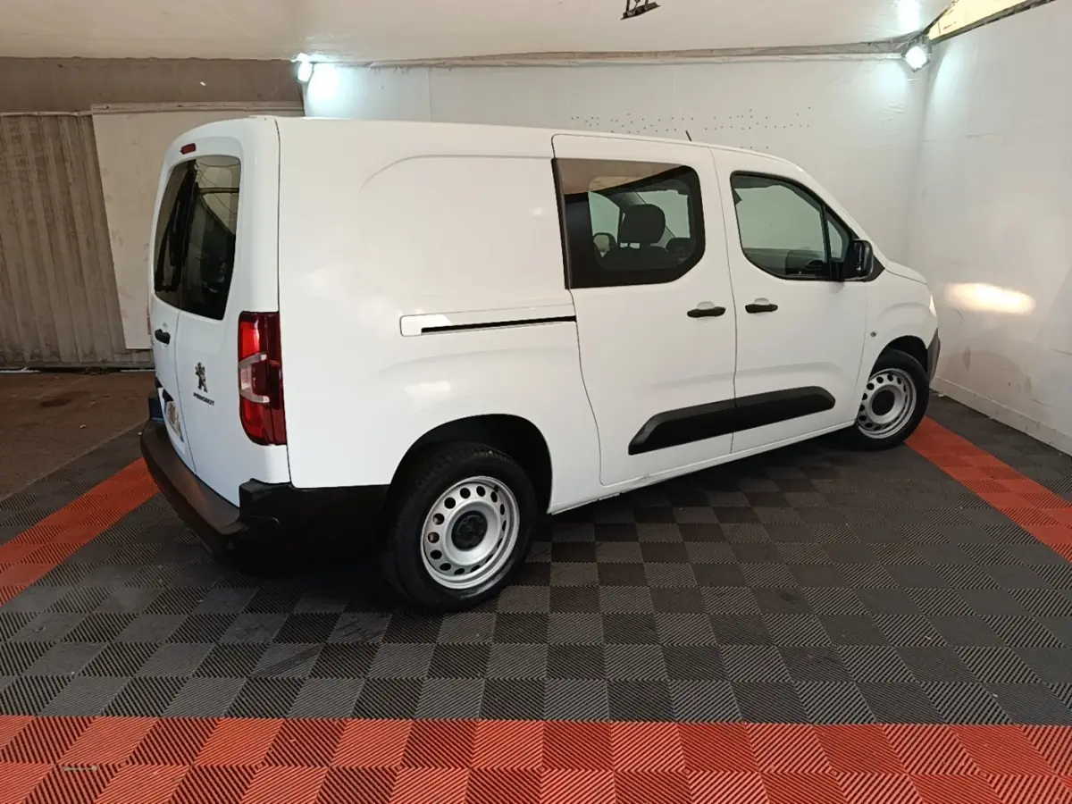 Vue 3/4 arrière droite d’un Peugeot Partner blanc 2020 en fourgon avec vitres latérales et jantes acier.