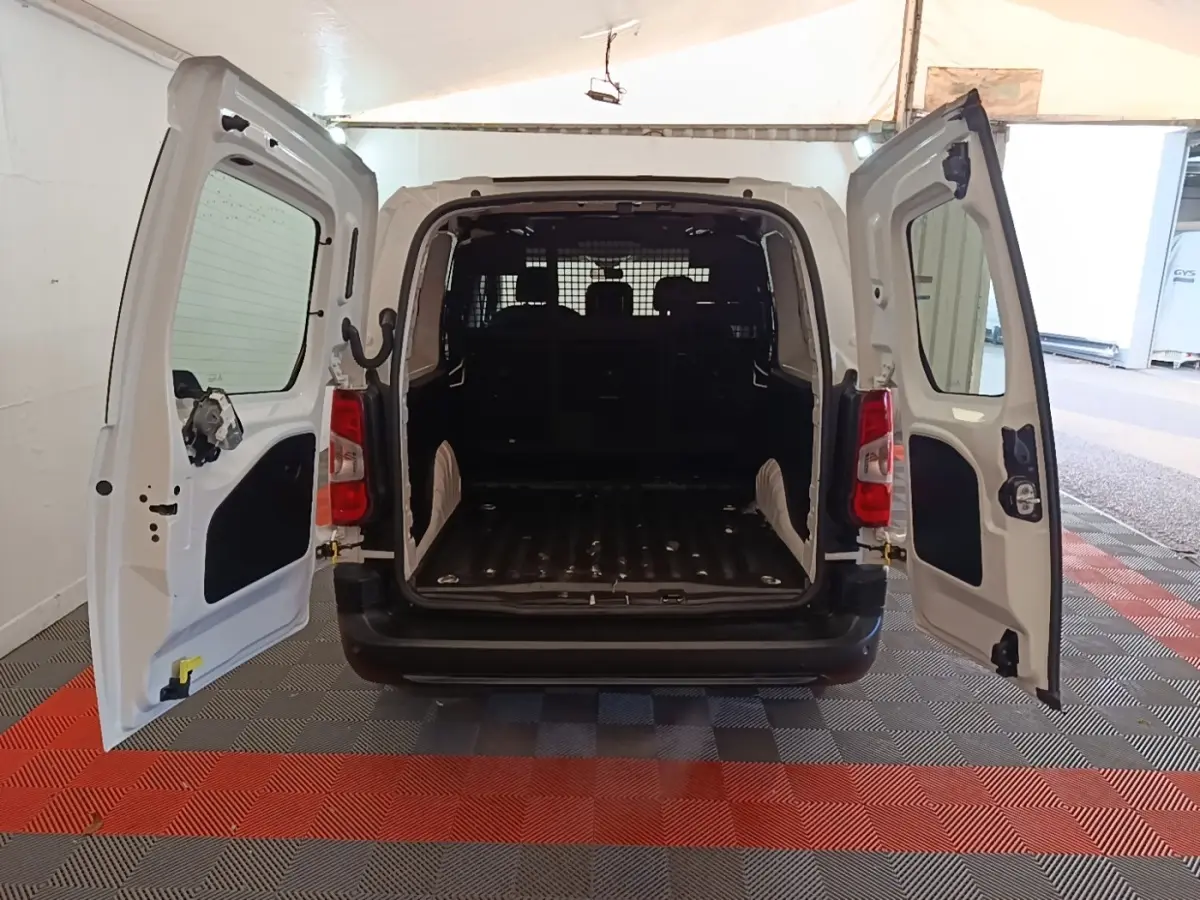 Vue arrière du Peugeot Partner blanc 2020 avec portes battantes ouvertes et cloison grillagée visible dans l’espace de chargement.
