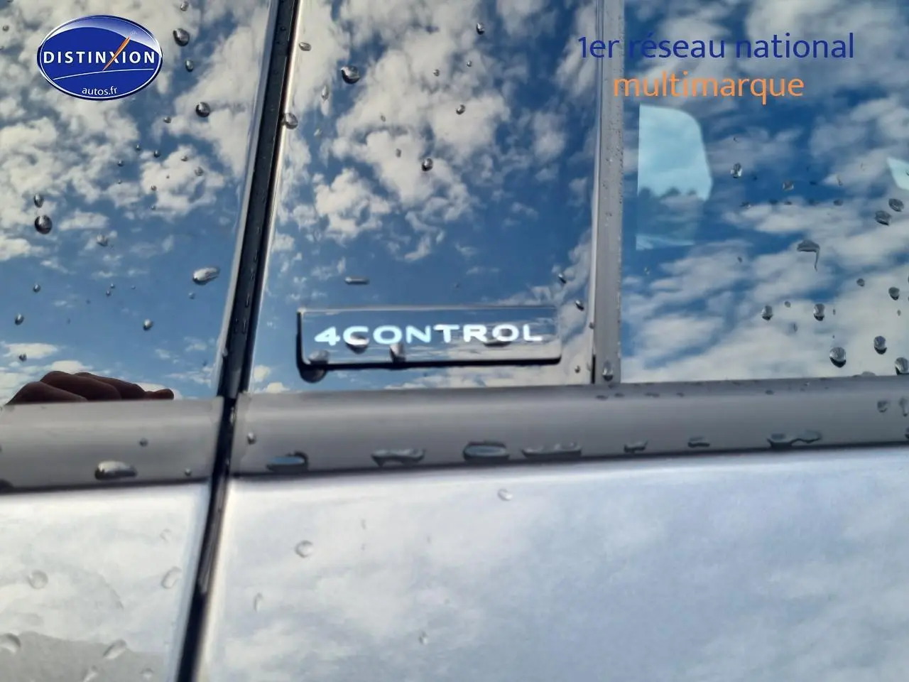 Gros plan sur l’inscription 4CONTROL sur la porte côté gauche d’un Renault Espace VI gris schiste sous la pluie.