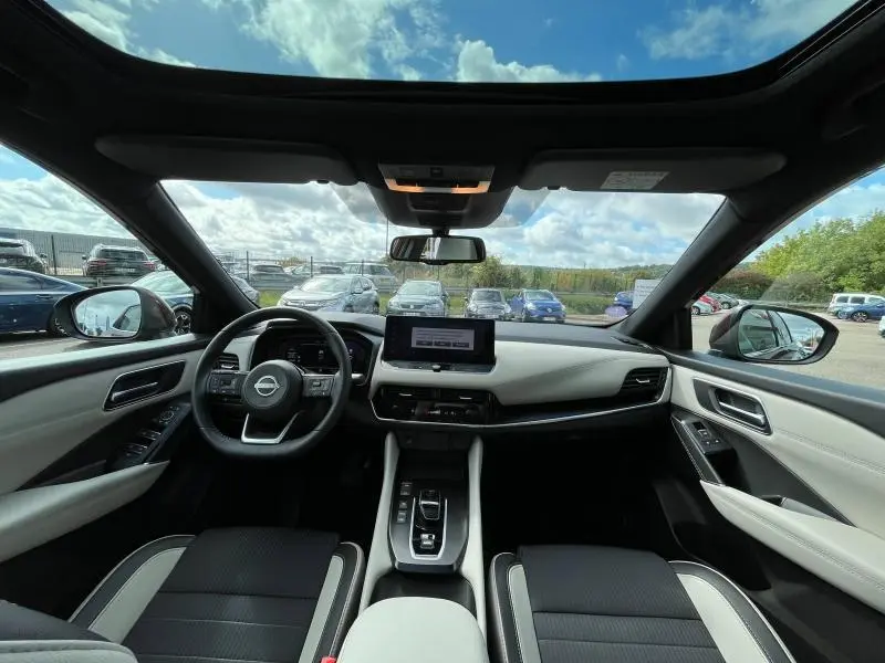 Intérieur du Nissan Qashqai e-POWER 2023 vu de face, tableau de bord moderne avec écran central et sellerie noire et grise.