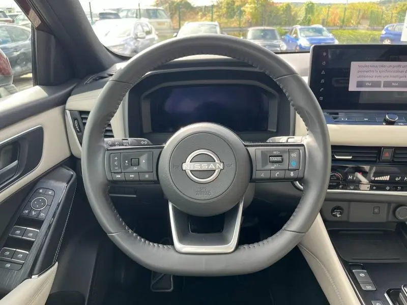 Vue centrée sur le volant cuir du Nissan Qashqai e-POWER 2023 avec tableau de bord et commandes intégrées visibles.
