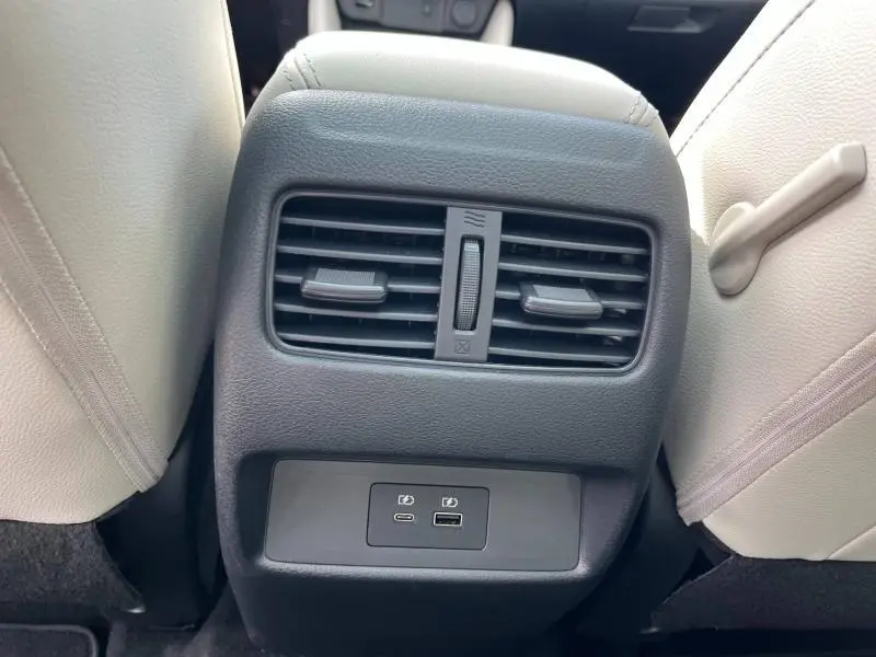 Prise USB et aérateurs arrière noirs entre sièges beige clair dans Nissan Qashqai e-POWER Tekna+ 2023