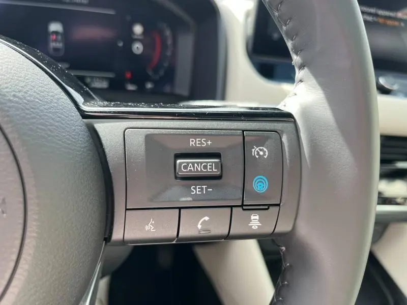 Gros plan sur les commandes au volant côté droit du Nissan Qashqai e-POWER 2023 avec cuir noir et tableau de bord numérique.