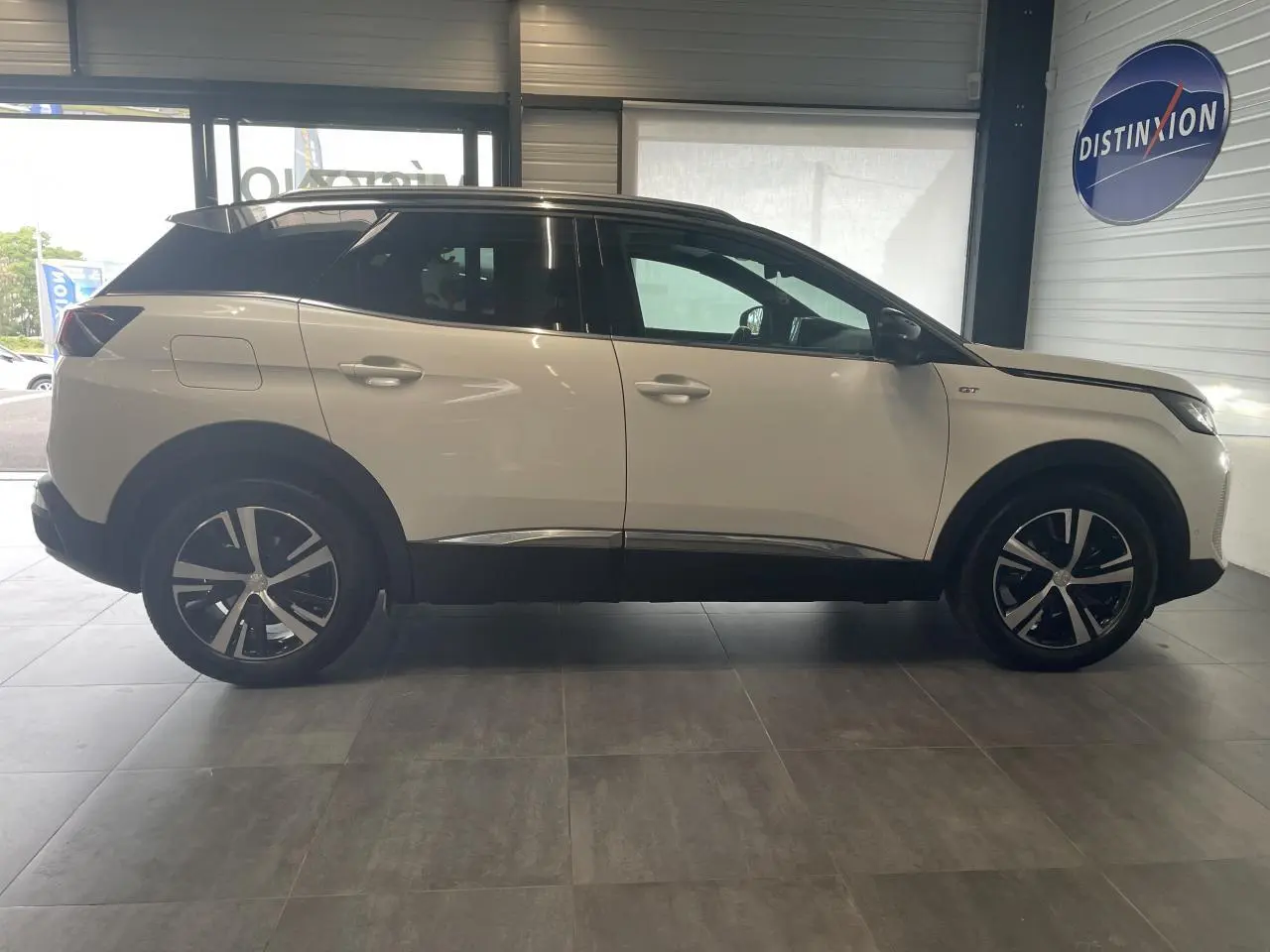 Peugeot 3008 GT blanc nacré en profil droit, toit noir, jantes alliage bi-ton et détails chromés visibles.
