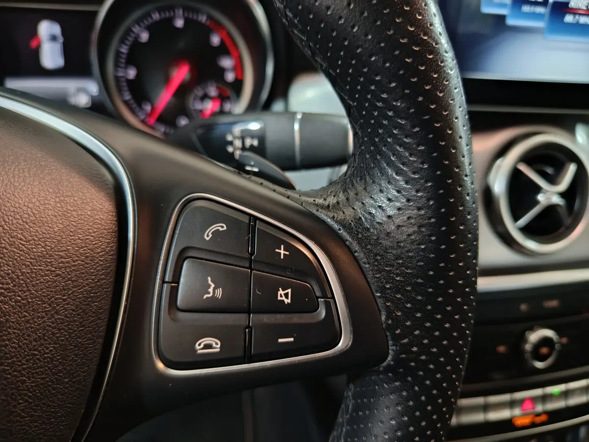 Gros plan sur le volant cuir noir perforé et commandes multifonctions du Mercedes GLA 200 d Business Executive 2018.