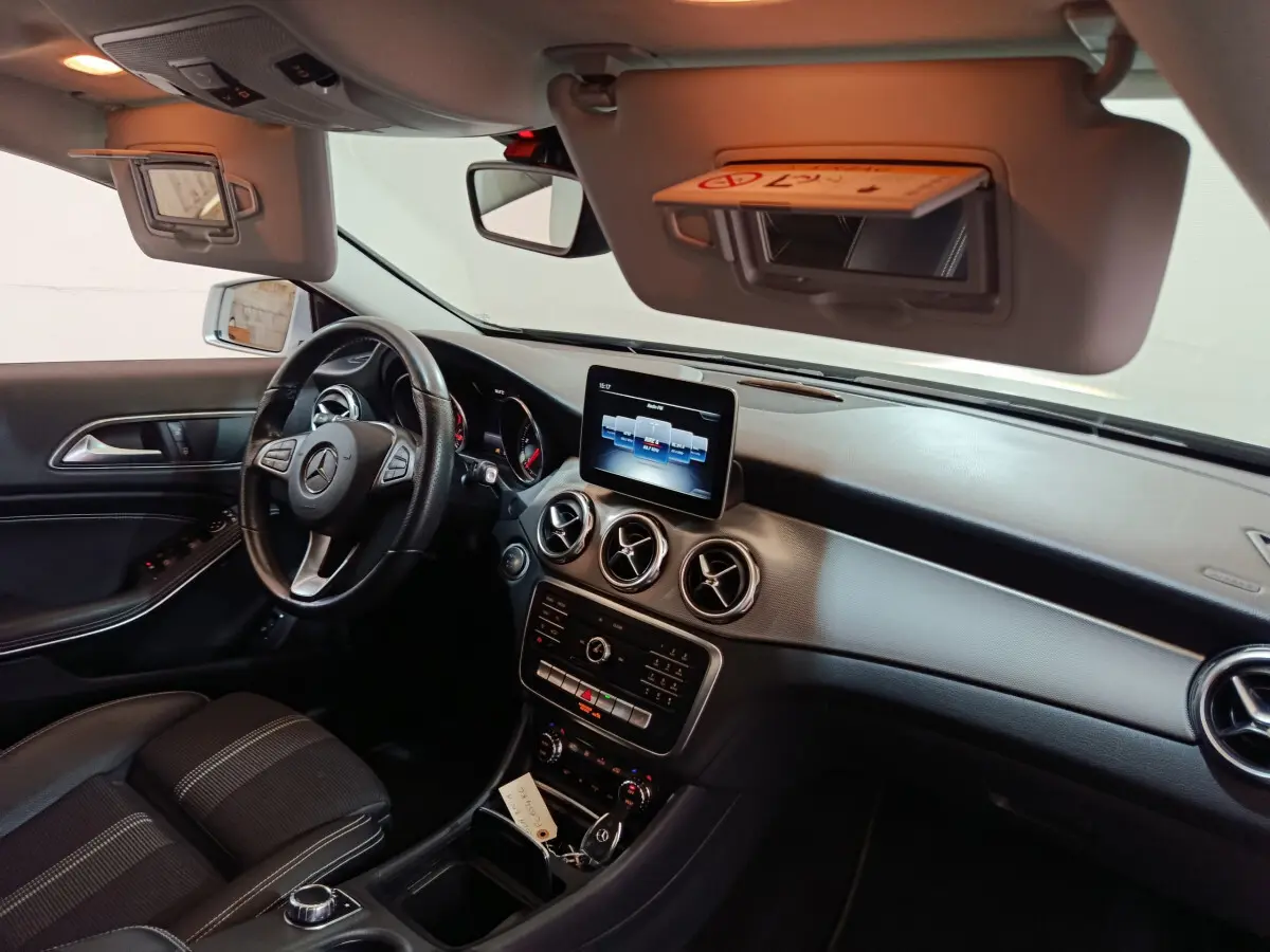 Vue intérieure côté conducteur du Mercedes GLA 200 d 2018, tableau de bord noir avec écran central et volant cuir.