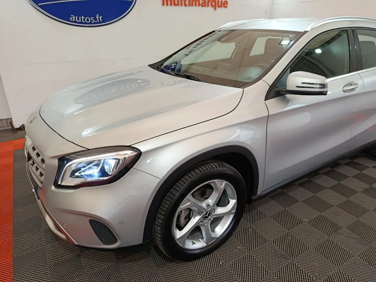 Vue 3/4 avant droit d'un Mercedes GLA 200 d gris clair avec phares LED allumés et jantes alliage cinq branches.