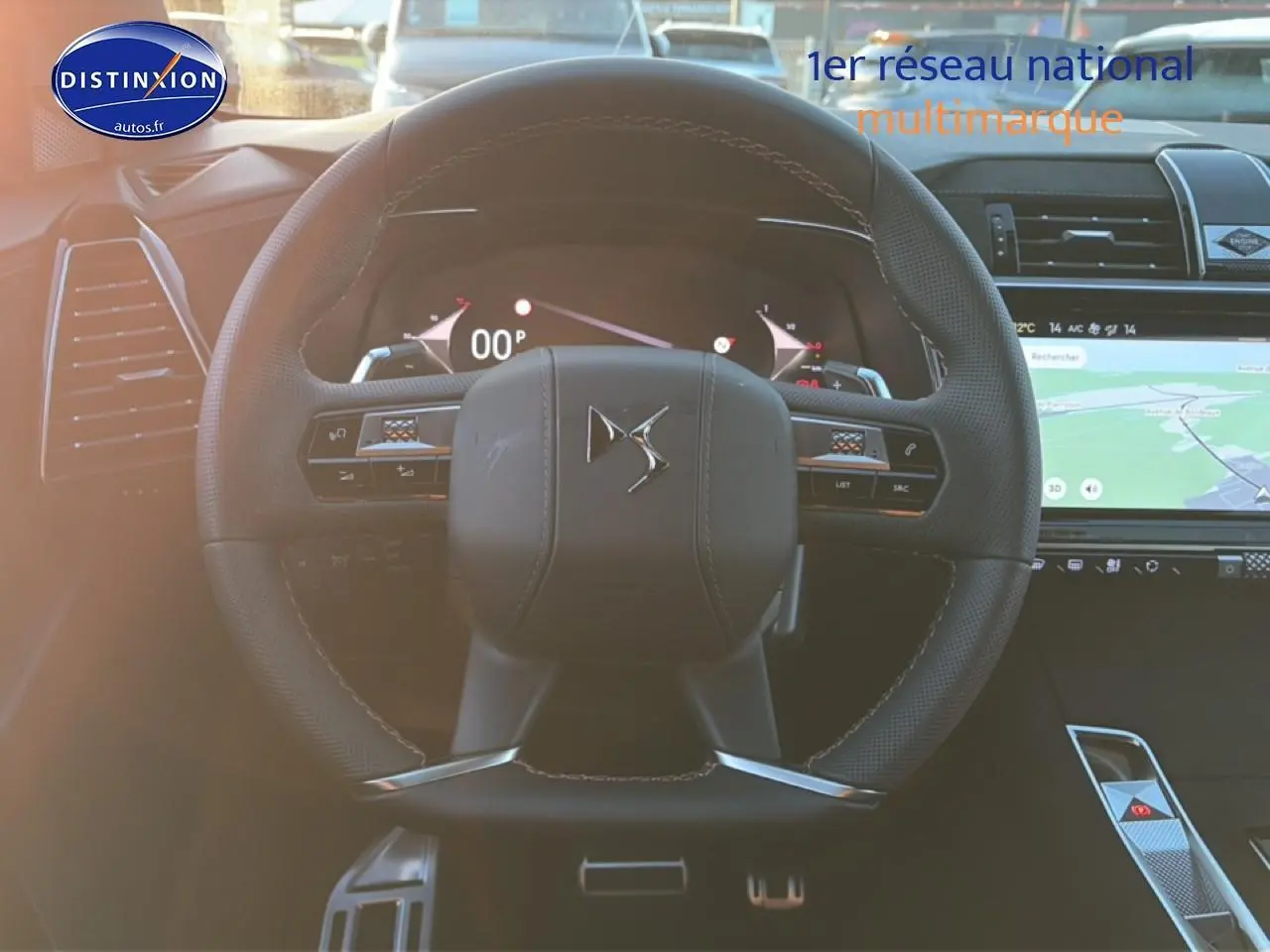 Vue frontale du volant cuir DS7 noir 2026 avec commandes intégrées et écran tactile GPS en arrière-plan.