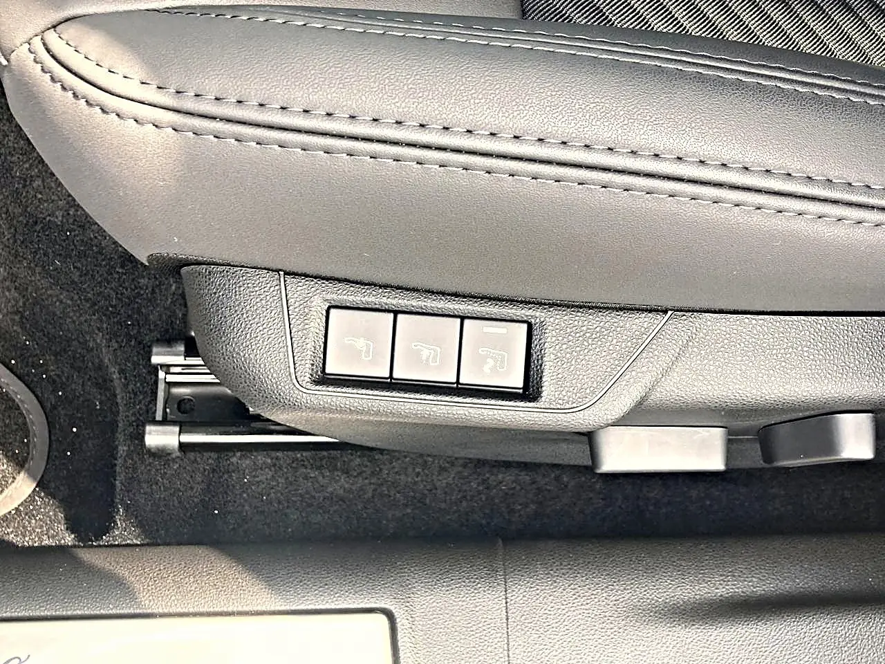 Gros plan sur les commandes électriques du siège conducteur noir de l'Alfa Romeo Junior 1.2 hybride gris 2026.
