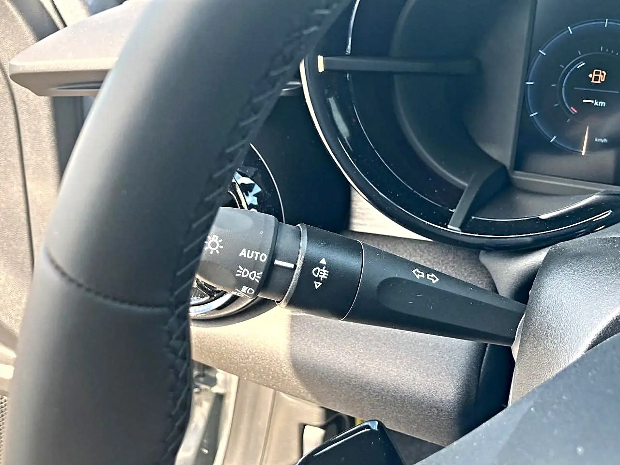 Gros plan sur le commodo d’éclairage à gauche du volant gris de l’Alfa Romeo Junior 1.2 hybride 2026.