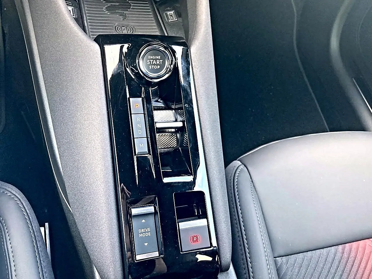 Vue rapprochée de la console centrale noire brillante avec bouton start/stop et levier de boîte automatique sur Alfa Romeo Junior gris.