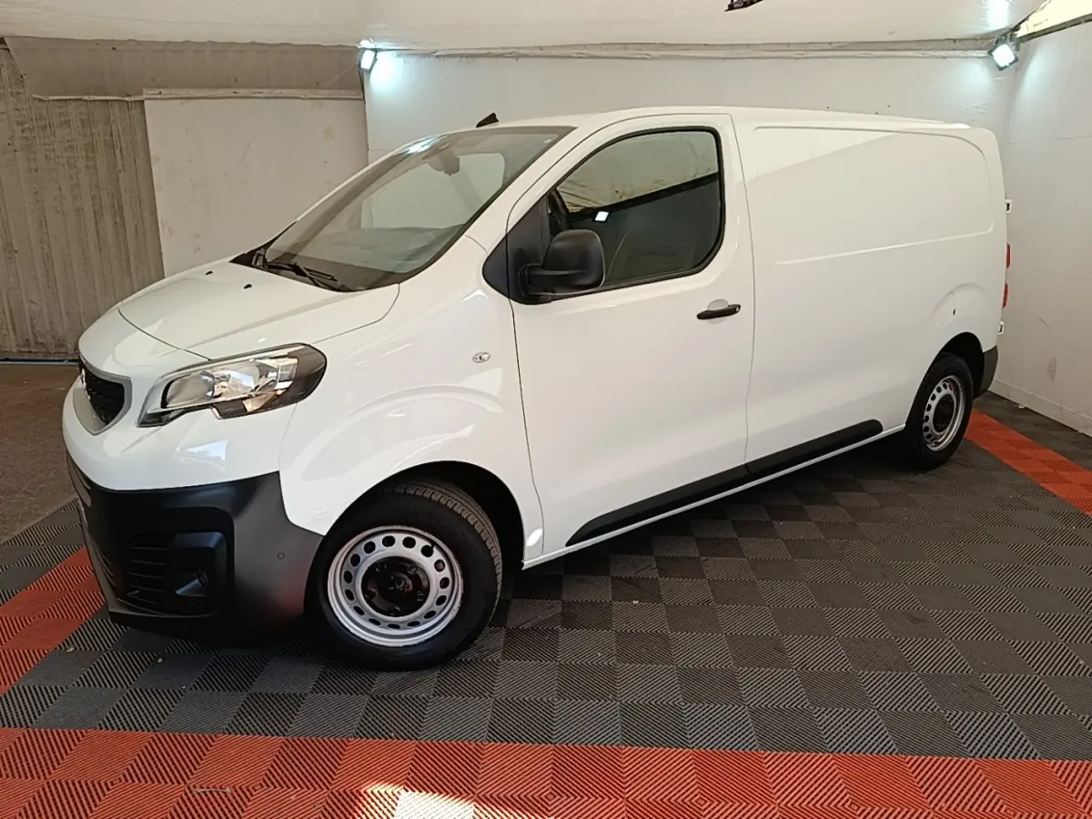 Vue 3/4 avant droit du Peugeot Expert Fourgon blanc avec pare-chocs noirs et jantes acier en intérieur fermé.