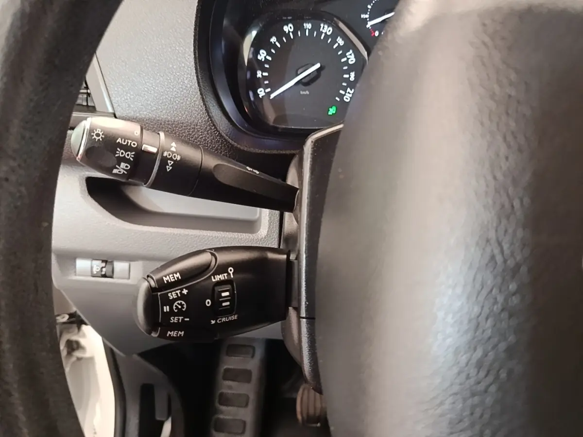 Vue rapprochée du volant côté gauche du Peugeot Expert Fourgon blanc, montrant commandes de régulateur et éclairage.