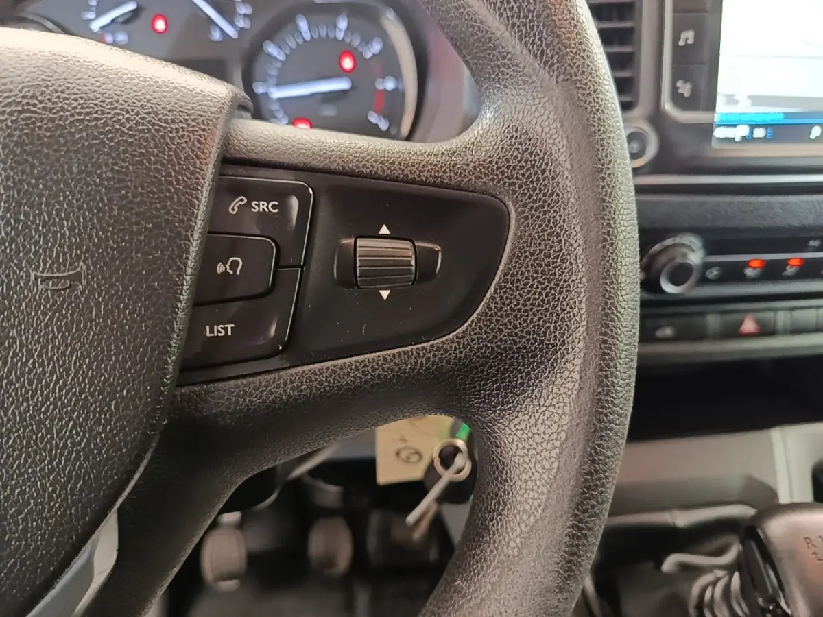 Gros plan sur le volant noir du Peugeot Expert Fourgon 2020, avec commandes audio et tableau de bord en arrière-plan.