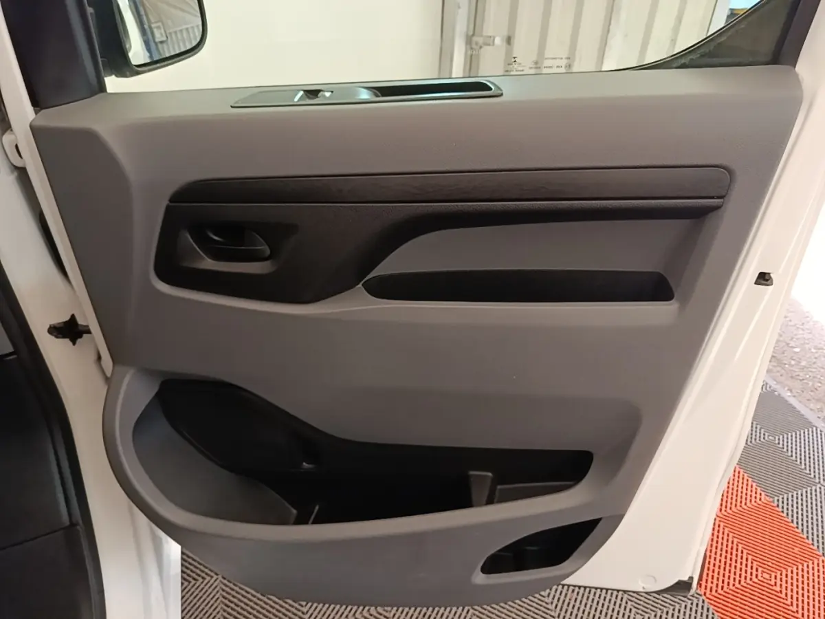 Vue rapprochée de la porte intérieure côté conducteur du Peugeot Expert Fourgon blanc, avec poignée noire et rangements intégrés.