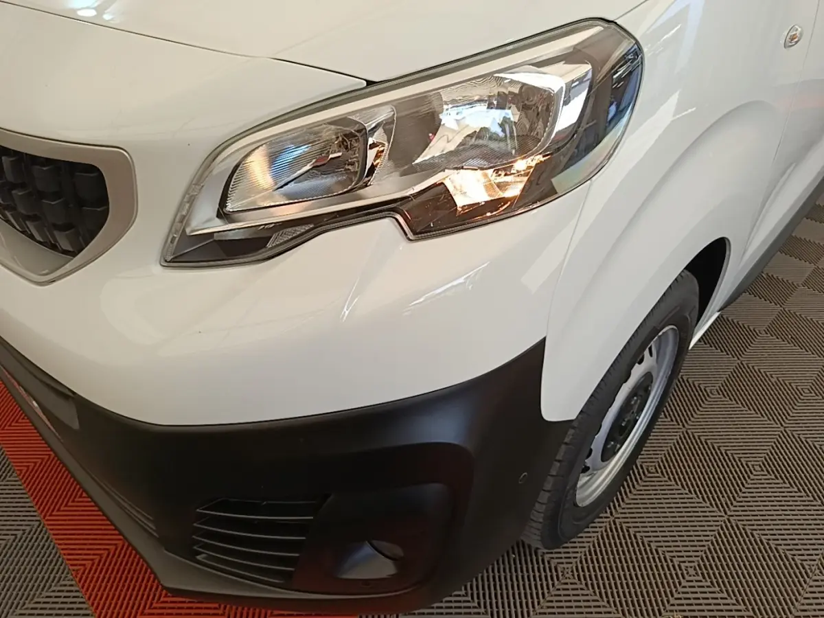 Gros plan sur l'avant droit blanc du Peugeot Expert Fourgon 2020, mettant en valeur le phare et le pare-chocs noir.