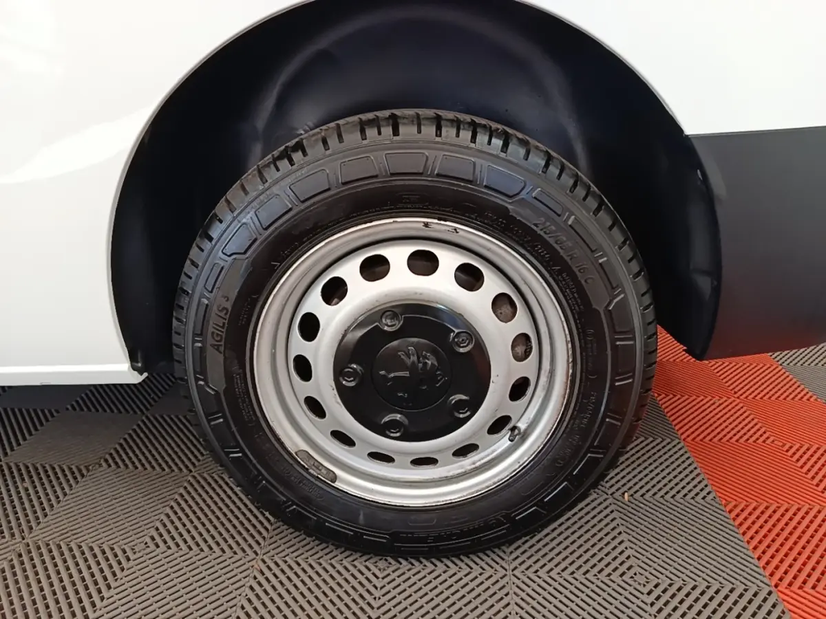 Gros plan sur la roue arrière droite en jante acier du Peugeot Expert Fourgon blanc, avec logo Peugeot visible au centre.