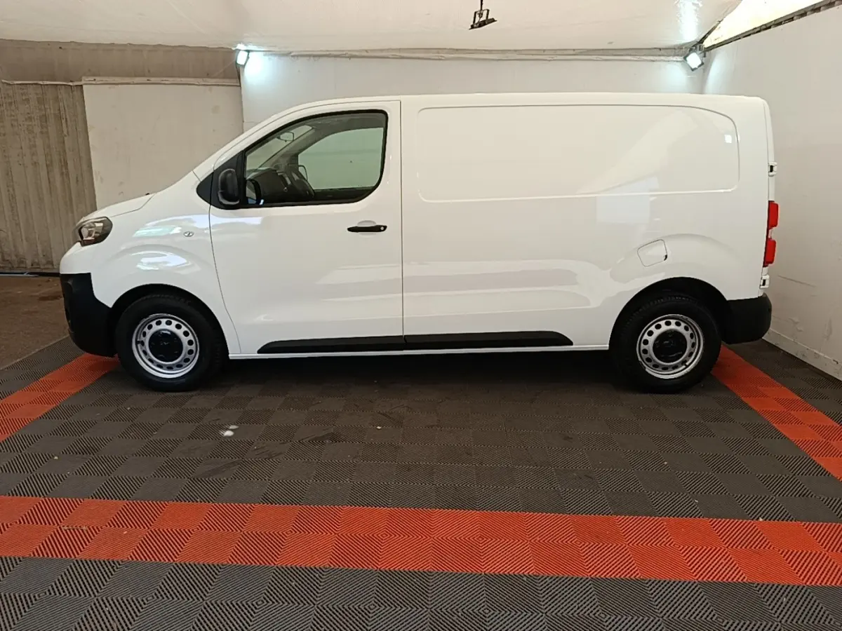 Profil côté gauche d’un fourgon Peugeot Expert blanc, version Standard Asphalt, sur sol à damier noir et rouge.
