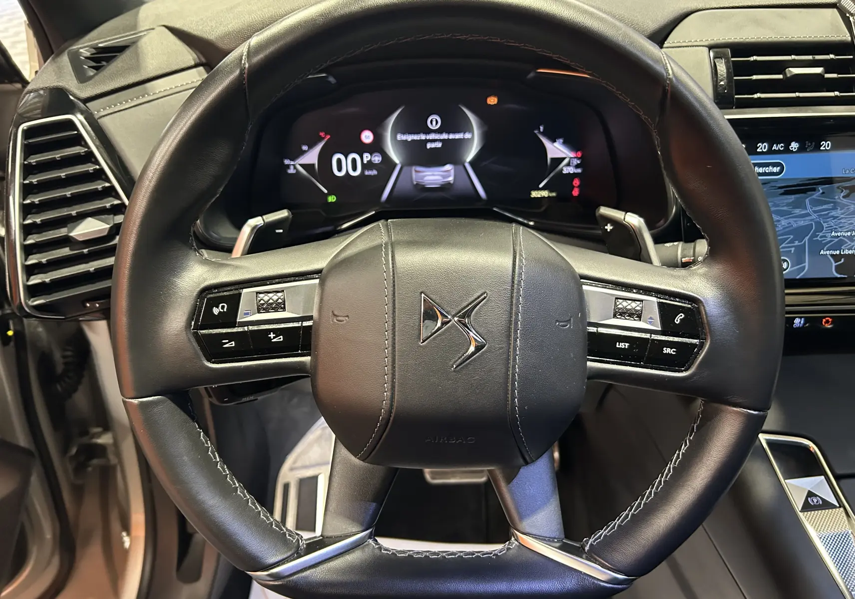 Volant en cuir noir avec logo DS au centre, tableau de bord numérique et écran tactile de navigation du DS7 2024.