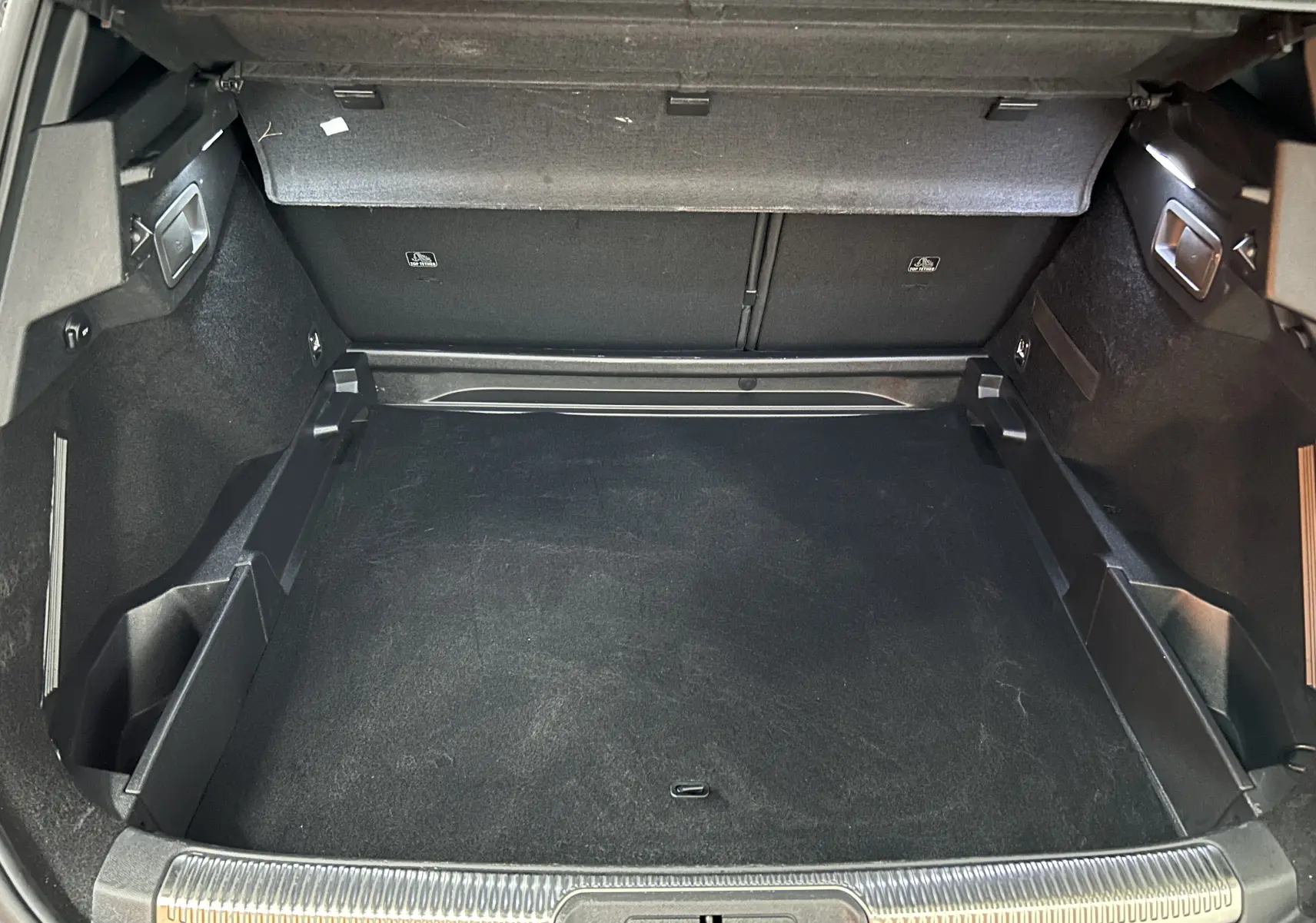 Coffre spacieux du DS7 BlueHDI 130 en vue intérieure, avec revêtement noir et hayon électrique visible.