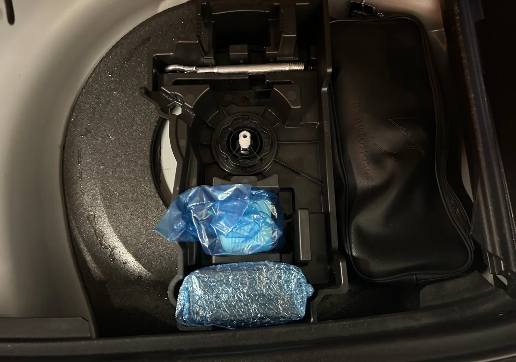 Coffre ouvert du DS7 BlueHDI 130 2024, vue plongeante sur rangement avec outils et trousse noire DS Automobiles.