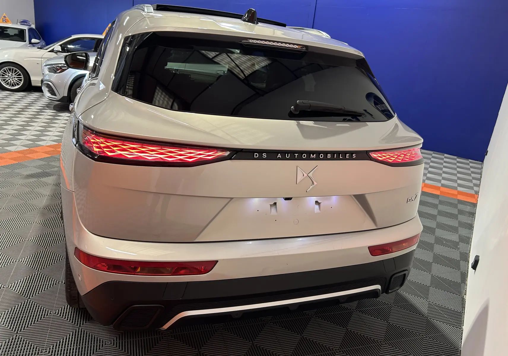 Vue arrière du DS7 2024 en Chrystal pearl, mettant en valeur son hayon électrique et ses feux arrière LED distinctifs.