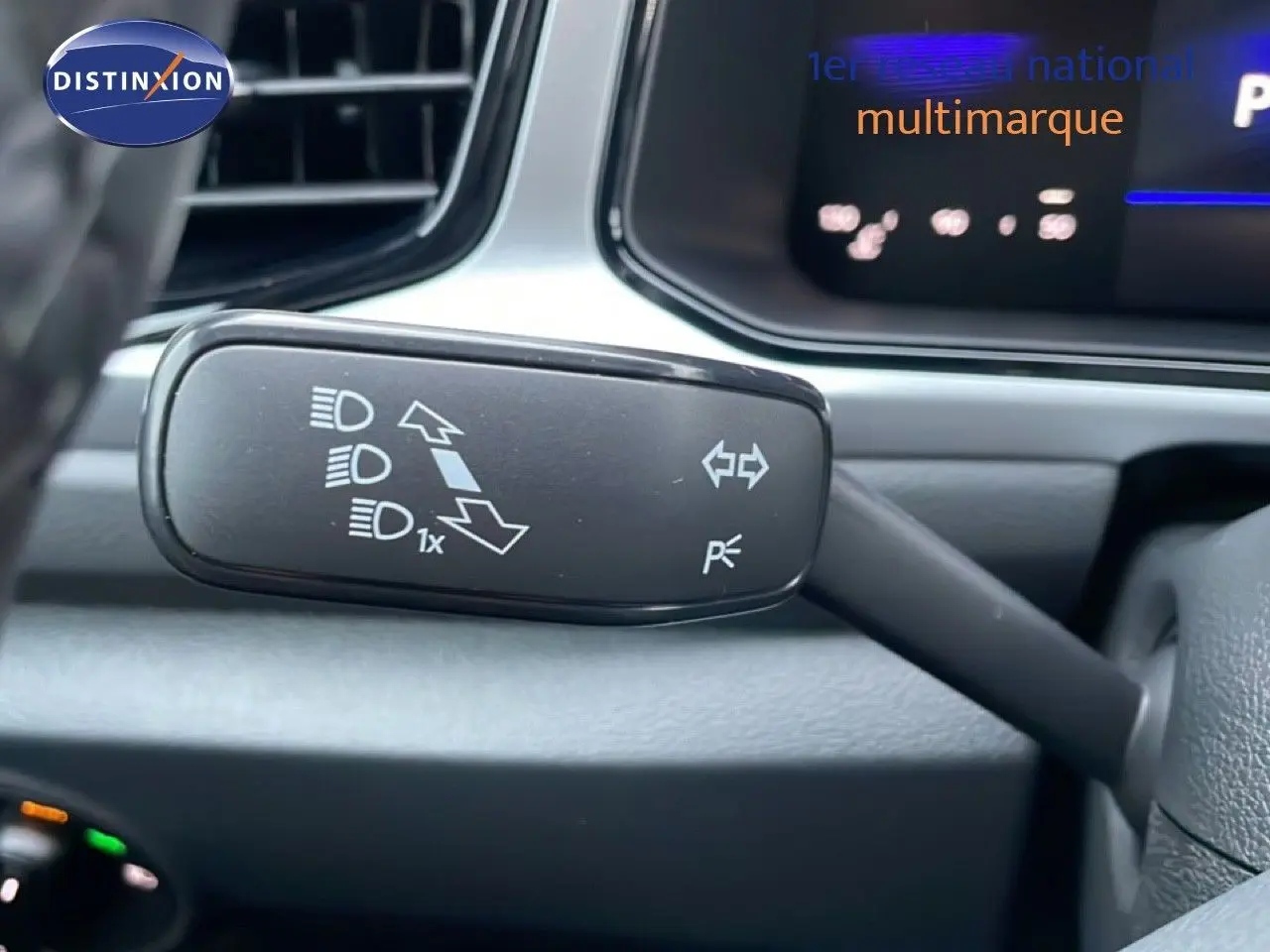 Gros plan sur le commodo gauche du volant du Volkswagen T-Roc noir grenadilla, avec commandes des feux et clignotants.