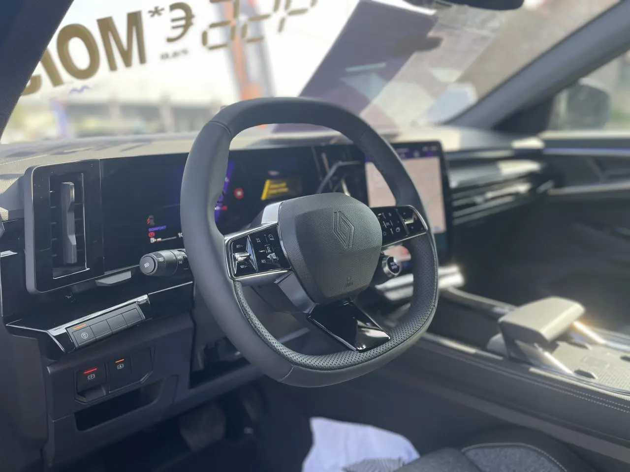 Vue intérieure centrée sur le volant noir de la Renault Rafale 2025 avec tableau de bord numérique et écran tactile.