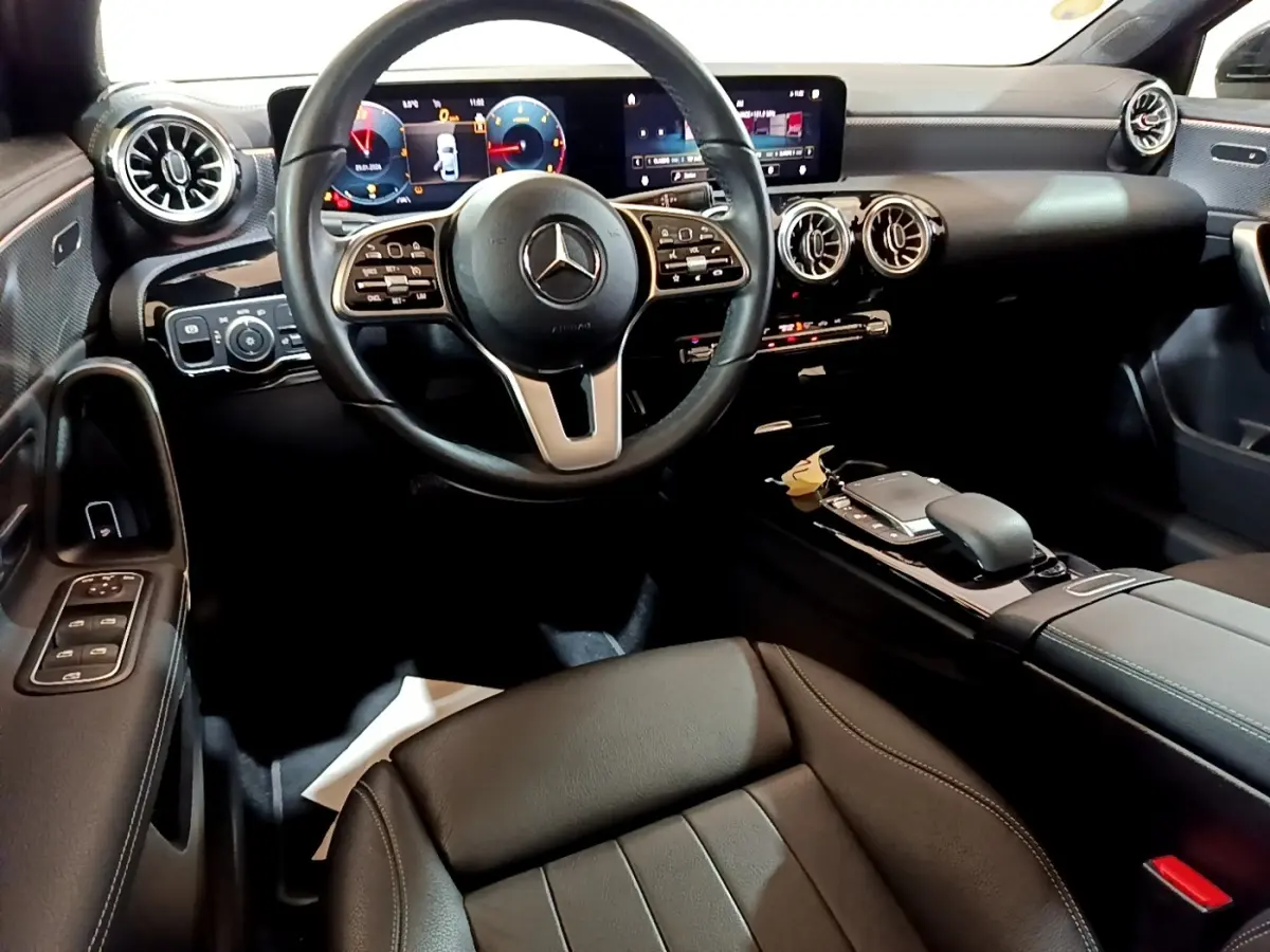 Vue intérieure avant de la Mercedes Classe A 200 d Progressive Line 2022, tableau de bord numérique et volant cuir noir.