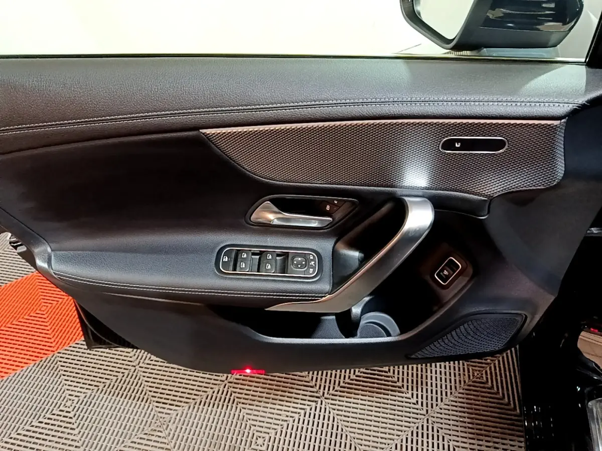 Vue rapprochée de la porte avant gauche noire de la Mercedes Classe A 200 d avec commandes électriques et insert décoratif.