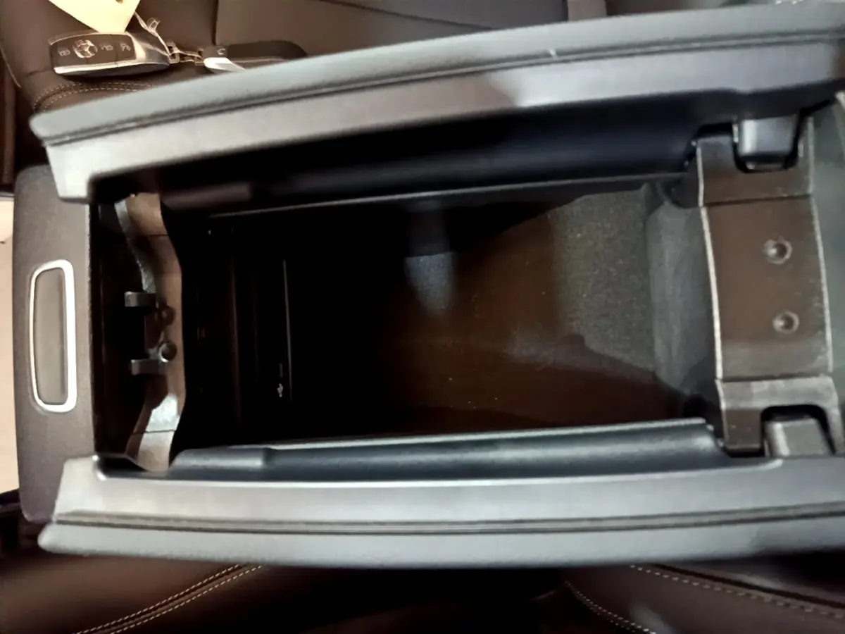 Vue plongeante sur le rangement central ouvert de la Mercedes Classe A berline noire, avec clé sur le siège en cuir noir.