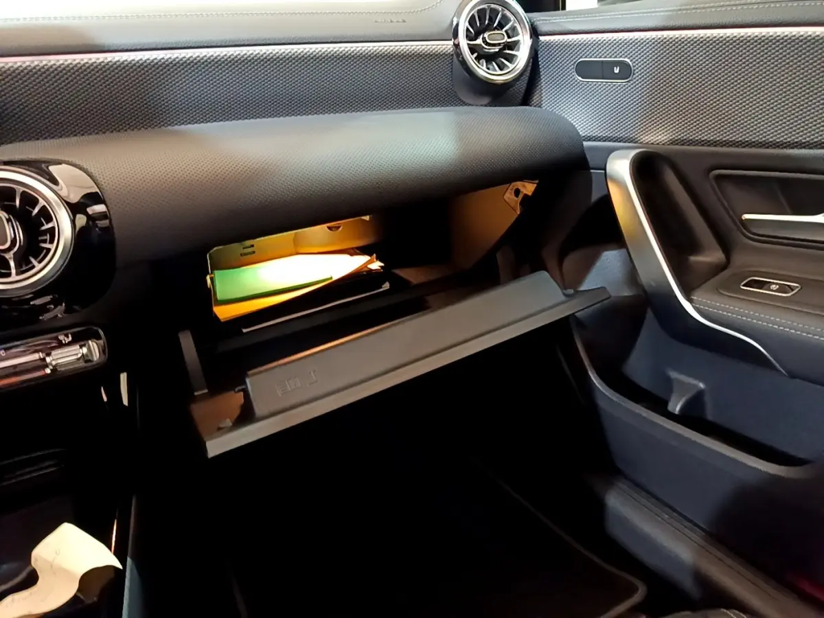 Intérieur de la Mercedes Classe A 200 d 2022, vue côté passager sur la boîte à gants ouverte avec éclairage intérieur.