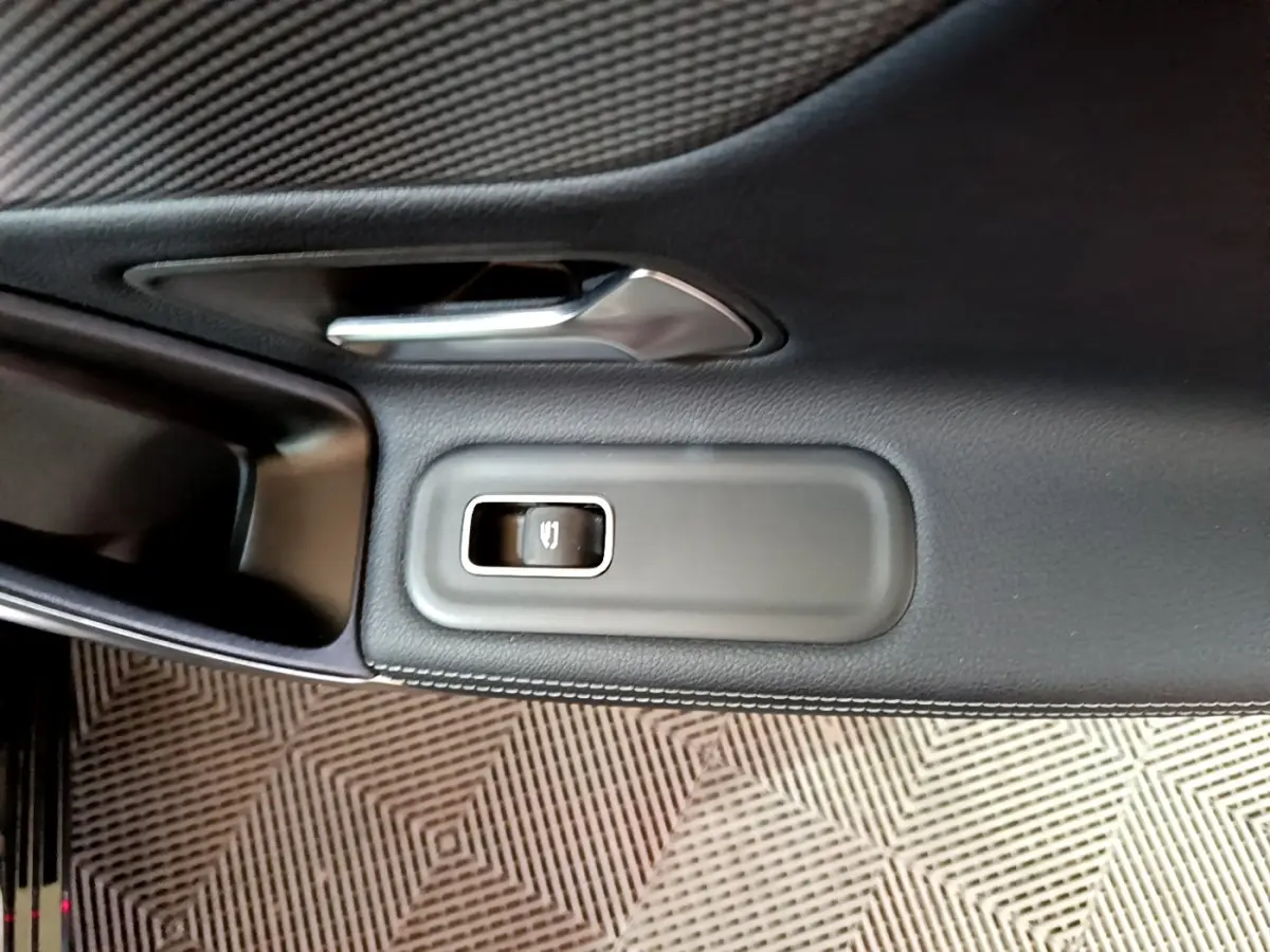 Gros plan sur la poignée de porte intérieure noire et le bouton de verrouillage d’une Mercedes Classe A Berline A 200 d Progressive Line 2022.
