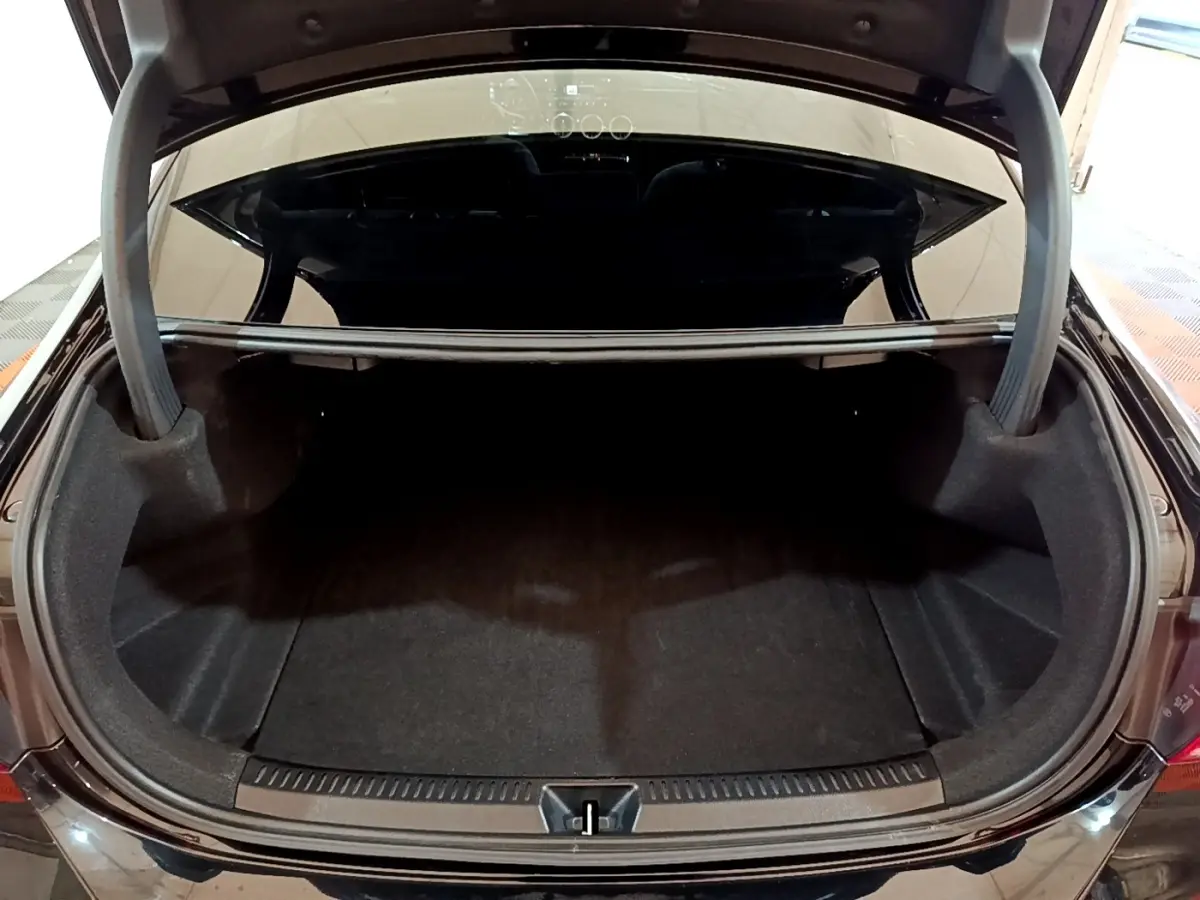 Coffre ouvert vu de l'arrière d'une Mercedes Classe A Berline noire, espace de rangement vide et propre.