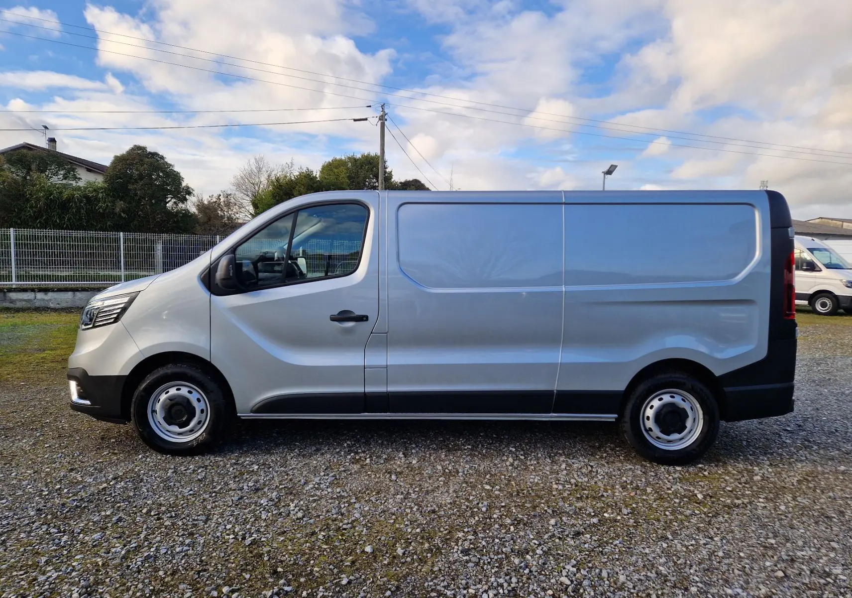 Vue de profil côté gauche du Renault Trafic Fourgon gris Highland 2025 avec porte coulissante et jantes acier.