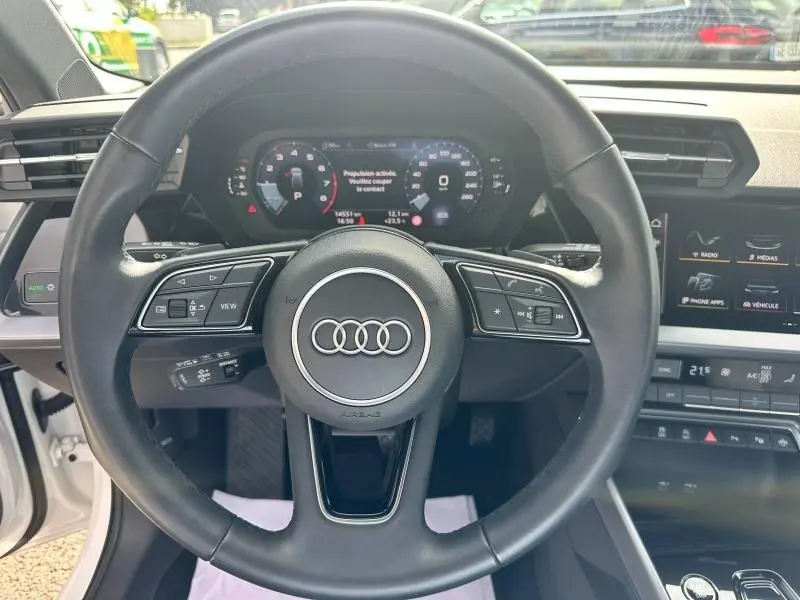 Vue intérieure centrée sur le volant cuir multifonction de l'Audi A3 Sportback 2024, tableau de bord numérique visible.