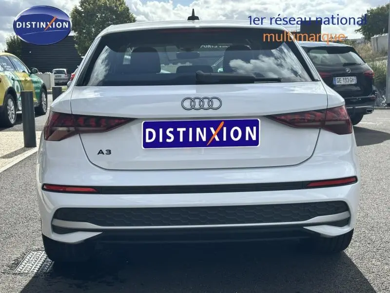 Vue arrière d'une Audi A3 Sportback 30 TFSI blanche Arkona avec feux arrière LED et logo Audi visible.