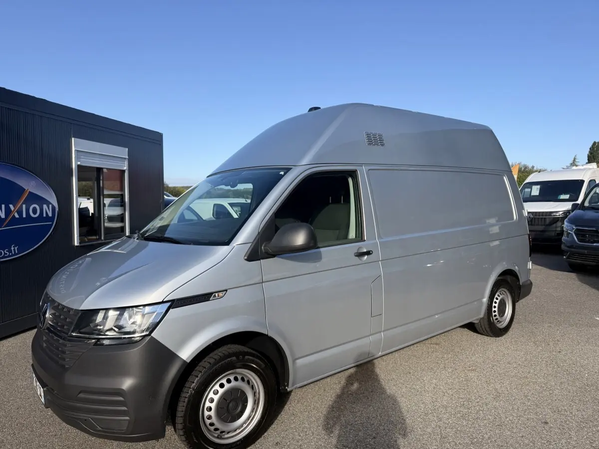 Vue 3/4 avant droit d’un Volkswagen Transporter gris clair version 2.0 TDi 110 L2H1 Business avec jantes acier.