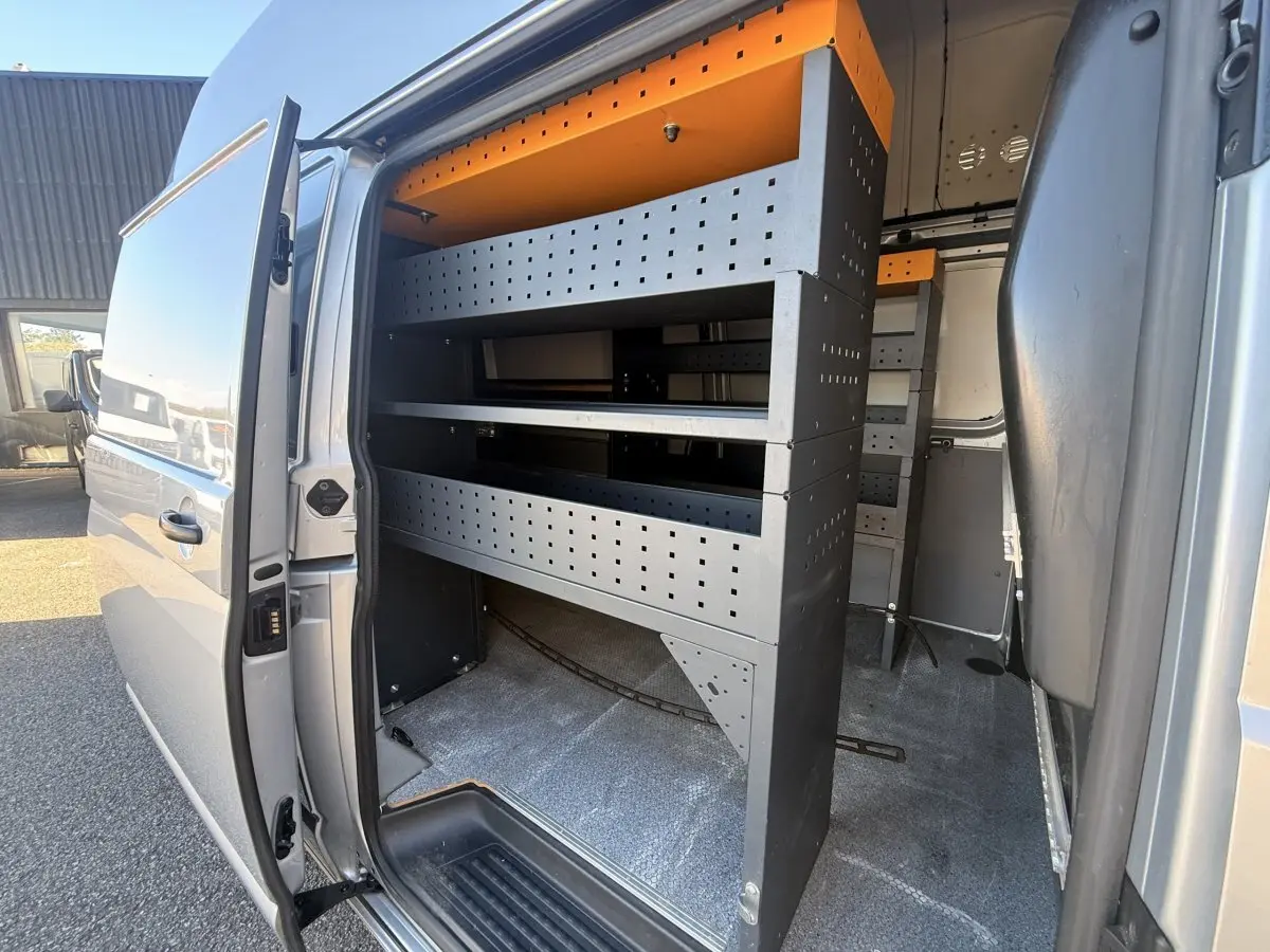 Vue latérale droite du Volkswagen Transporter gris clair 2022 avec porte coulissante ouverte et aménagements de rangement internes.