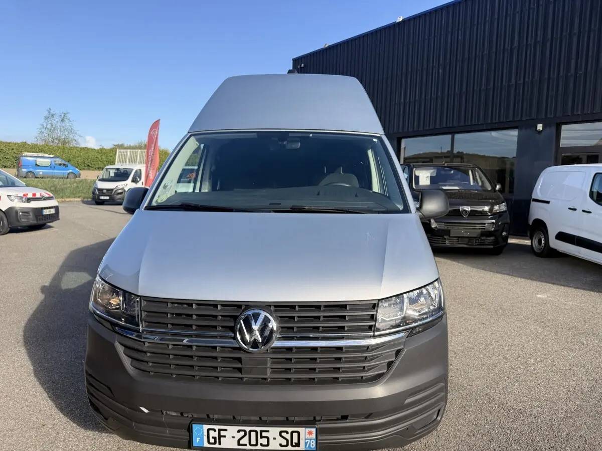 Vue avant d'un Volkswagen Transporter gris clair 2.0 TDi 110 L2H1 Business avec calandre noire et logo VW central.