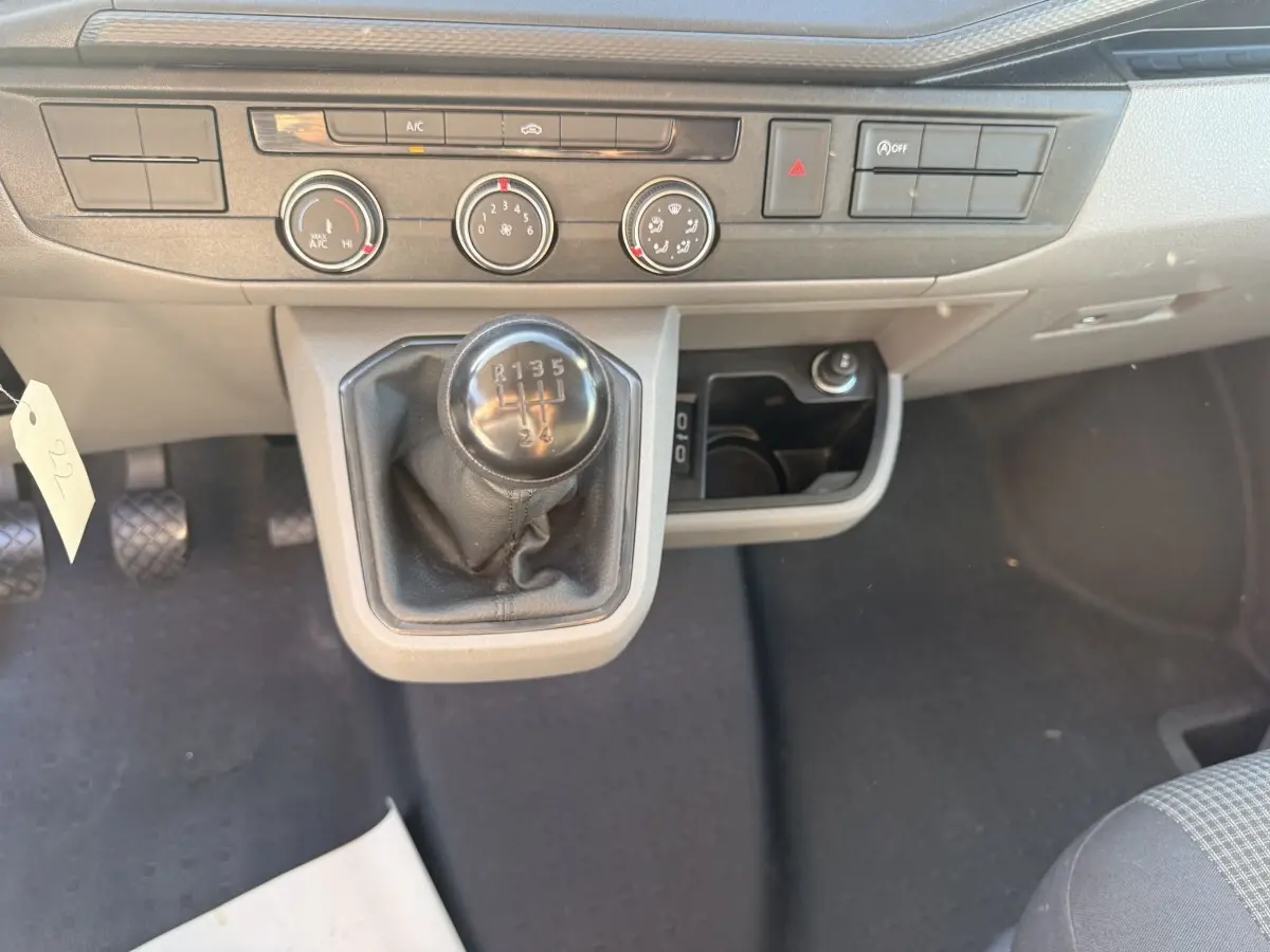 Gros plan sur la console centrale grise du Volkswagen Transporter 2.0 TDi 110 avec levier de vitesse manuel et commandes climatisation.