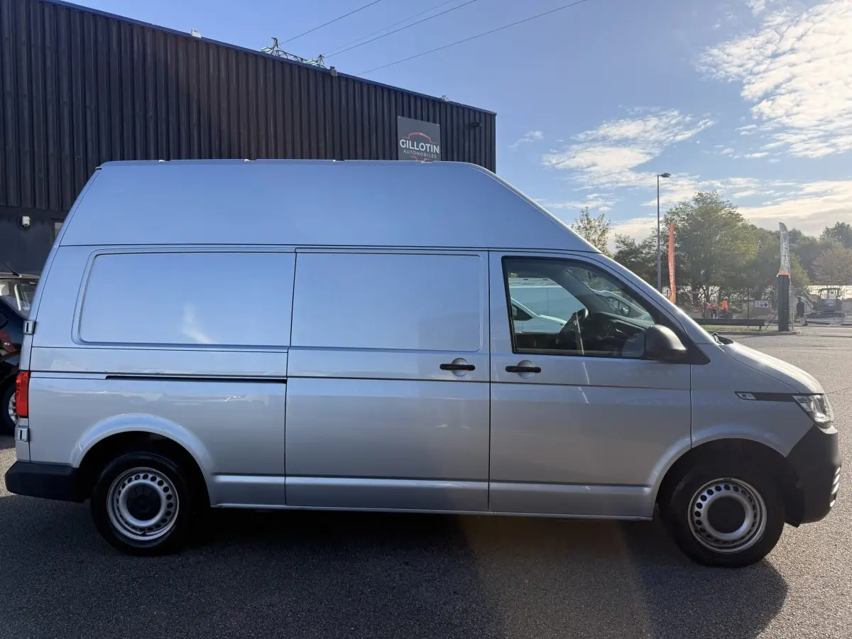 Vue de profil côté droit d’un Volkswagen Transporter gris clair 2.0 TDi 110 L2H1 Business avec toit surélevé.