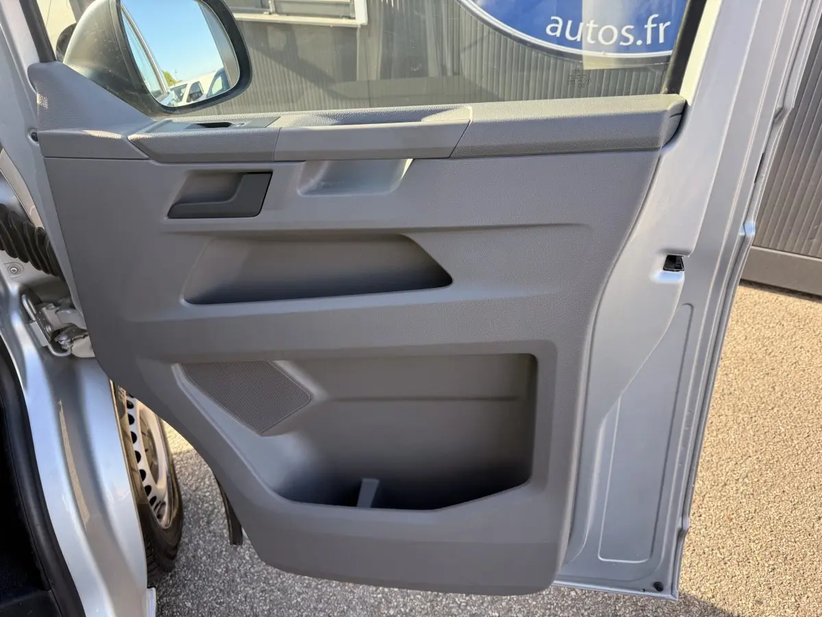 Vue rapprochée de la porte avant gauche grise claire du Volkswagen Transporter 2.0 TDi 110 L2H1 Business avec rangement intégré.
