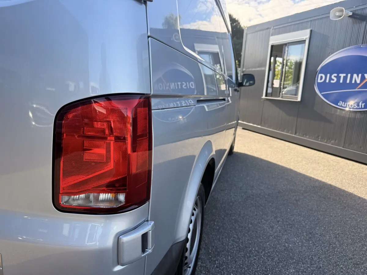 Vue arrière côté droit du Volkswagen Transporter gris clair, mettant en valeur le feu arrière et la carrosserie lisse.