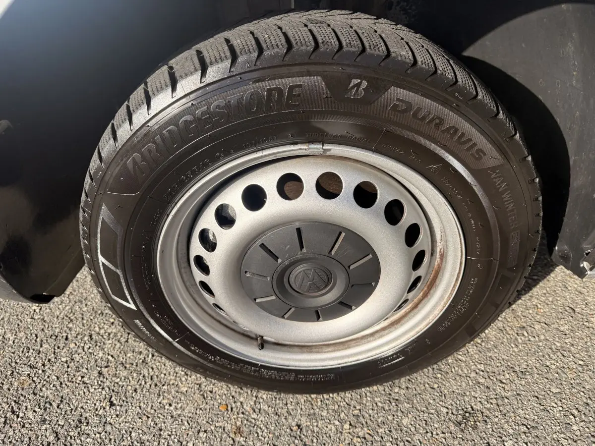 Gros plan sur la roue acier grise avec pneu Bridgestone hiver du Volkswagen Transporter gris clair 2022.