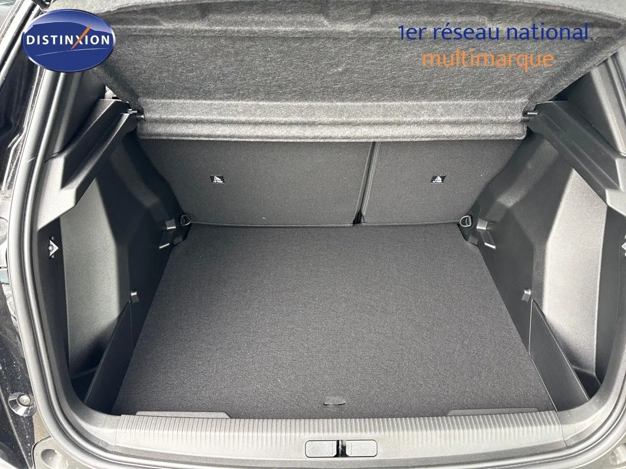 Coffre ouvert d'une Peugeot 2008 Hybrid noir métal, montrant l'espace de chargement vide et la doublure intérieure.