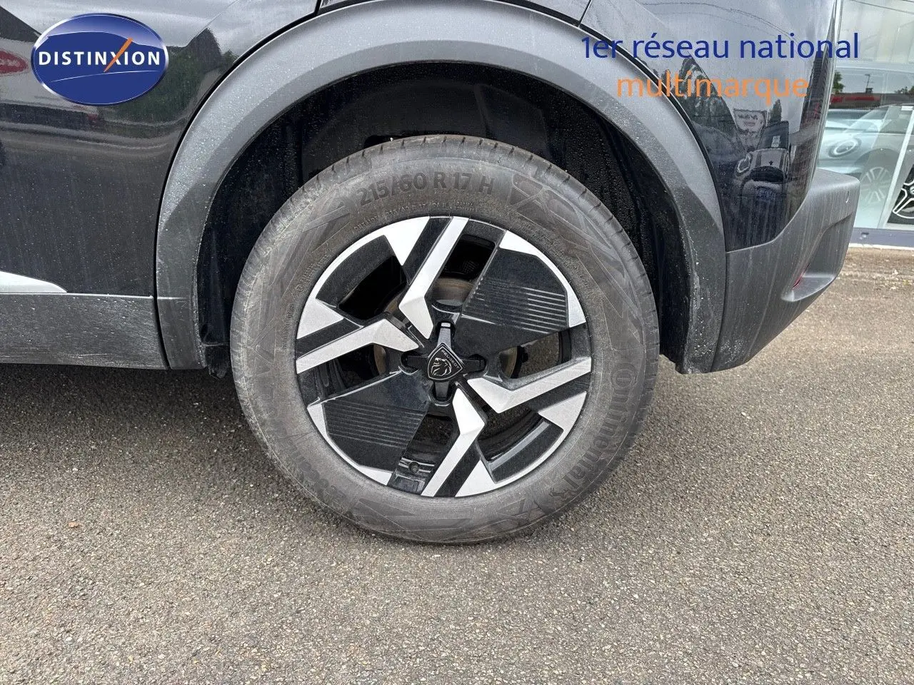 Gros plan sur la roue avant droite noire métal d'un Peugeot 2008 Hybrid 136ch Allure avec jante bi-ton distinctive.