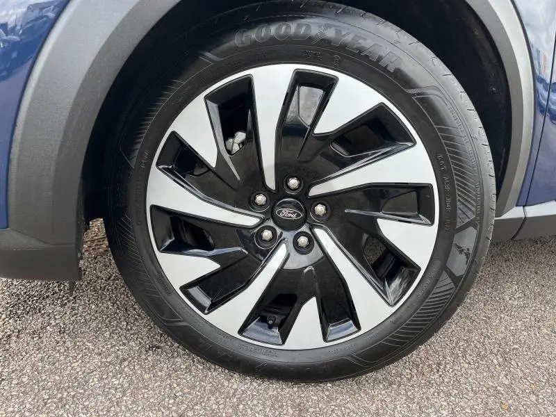 Gros plan sur la roue avant gauche du Ford Puma bleu Abysse 2023 avec jante alliage bicolore et pneu Goodyear.