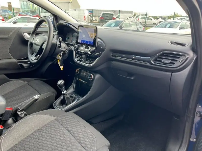 Intérieur avant droit du Ford Puma bleu avec tableau de bord noir, volant multifonction et écran tactile central.