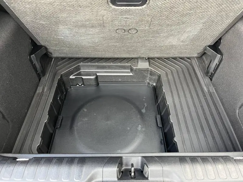 Coffre ouvert du Ford Puma 2023 montrant la roue de secours 16 pouces sous le plancher de coffre.